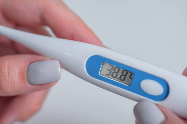 Mujer sosteniendo termómetro médico digital con alta temperatura - de cerca - Foto, Imagen