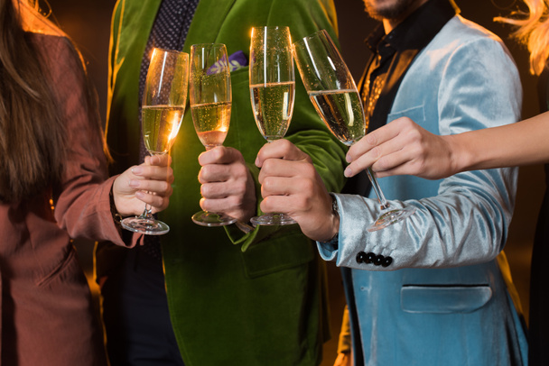 cropped view of friends toasting glasses of champagne on black  - Foto, afbeelding