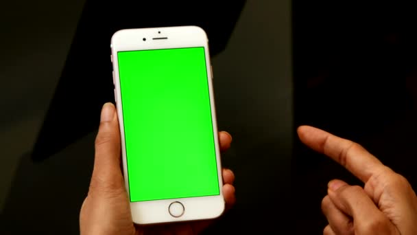 Gesti con le dita su un telefono cellulare o smartphone. Smart phone con schermo verde su sfondo scuro. Smartphone di colore bianco con schermo verde e movimento delle dita sullo schermo. - Filmati, video