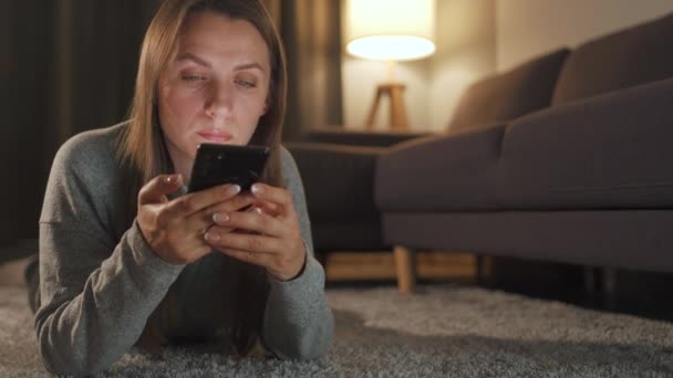 Mulher está deitada no chão e usando smartphone à noite - Filmagem, Vídeo