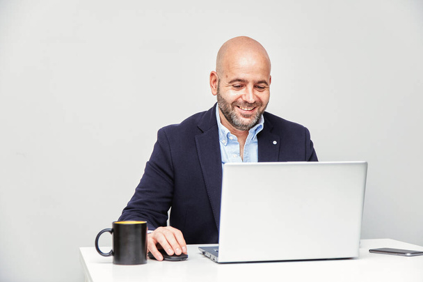 Ein selbstständiger Unternehmer, der von zu Hause aus mit einem Laptop arbeitet. Erwachsener Mann mit Glatze - Foto, Bild