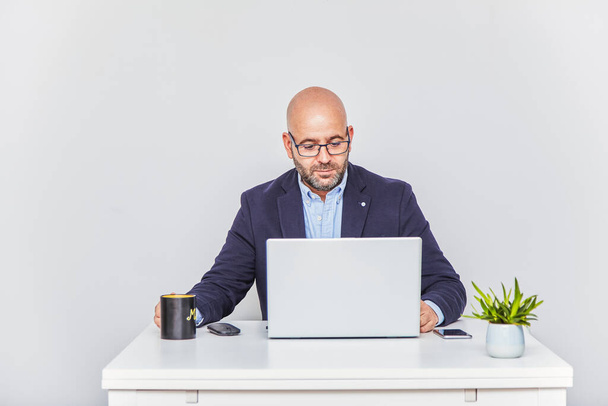 Um empresário autônomo que trabalha em casa com um laptop. Homem careca adulto com óculos - Foto, Imagem