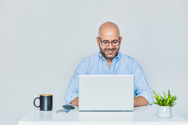 A self-employed entrepreneur working from home with a laptop. Adult bald man with glasses - Fotó, kép