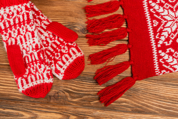 top view of red knitted scarf and mittens on wooden background - Foto, Imagen