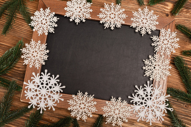 top view of winter snowflakes on chalkboard on wooden background - Фото, изображение