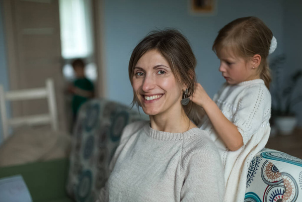 The daughter braids her mothers hair. Home furnishings. - Valokuva, kuva