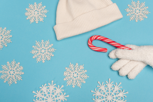 top view of winter white knitwear, candy cane and snowflakes on blue background - Photo, Image