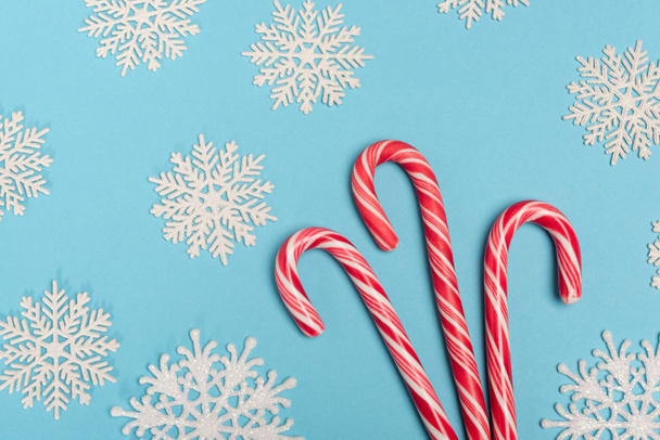 top view of candy cane and snowflakes on blue background - Фото, зображення