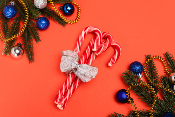 top view of decorated Christmas tree and candy canes on red background - Fotó, kép