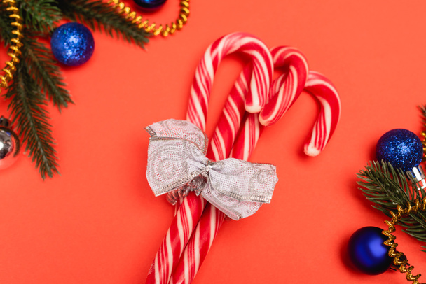 vrchní pohled na zdobené vánoční stromeček a candy canes na červeném pozadí  - Fotografie, Obrázek