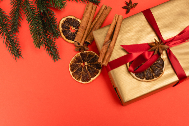 vue du dessus de l'arbre de Noël, cadeau avec des épices sur fond rouge - Photo, image