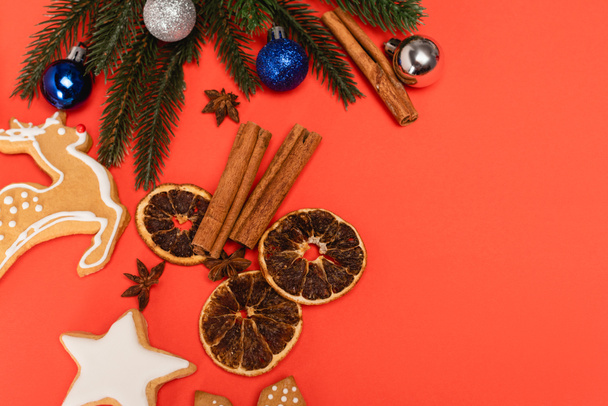 vue de dessus du sapin de Noël, des épices et des biscuits au pain d'épice sur fond rouge - Photo, image