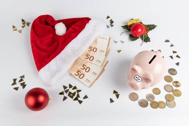Concetto di denaro e Natale: cappello di Babbo Natale e denaro in euro su sfondo bianco - Foto, immagini