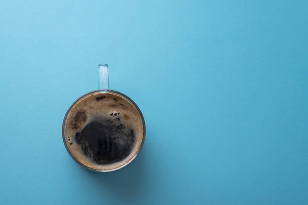 Стеклянная чашка кофе с пеной, на синем фоне. Место для текста. - Фото, изображение