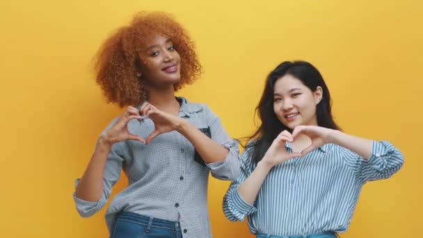 Concept d'amitié ou de relation multiraciale. afro-américain noir et asiatique femme faire coeurs avec mains - Séquence, vidéo