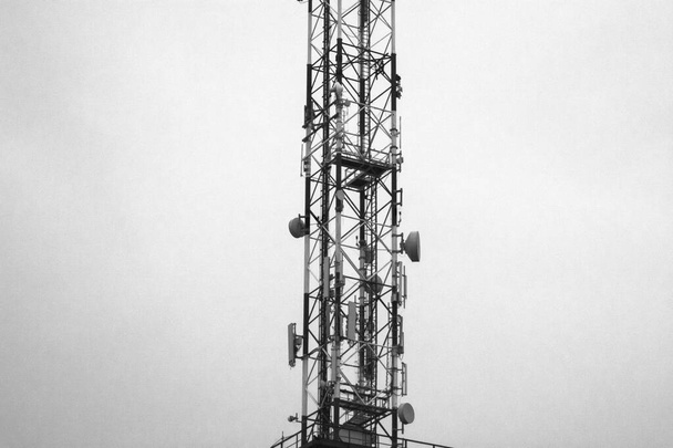 Part of a telecommunication pole at dusk. The night warning lights on the pole came on. - Zdjęcie, obraz