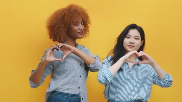多人種間の同性愛関係の概念。アフリカ系アメリカ人の黒人とアジア系の女性が手で心を作る - 映像、動画