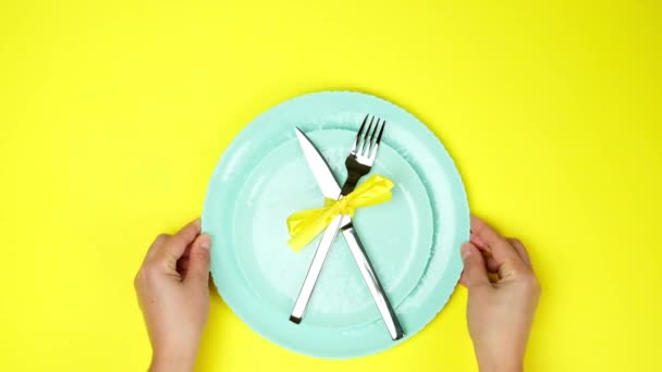 duas mãos femininas colocar faca de metal e garfo amarrado com fita amarela em placas vazias, vista superior, fundo amarelo, configuração de mesa - Filmagem, Vídeo