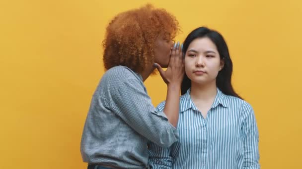 joven africano americano negro mujer susurrando a su asiático amigo expresando shock - Imágenes, Vídeo