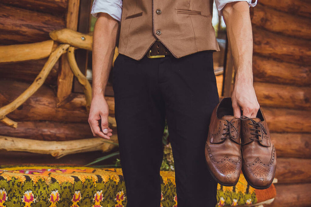 a groom and wedding shoes. Groom is wearing shoes outdoors. Male portrait of handsome guy. Beautiful model boy in colorful wedding clothes. Man is posing.  - Photo, Image