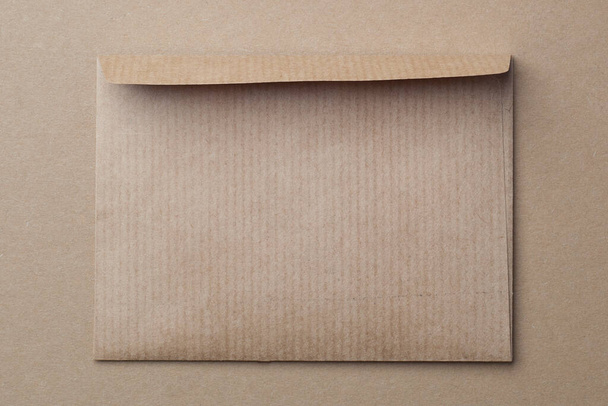 Braune Kraftpapier-Blanko-Karte und Umschlag auf Kraft-Hintergrund. Minimalismus. Ein Ton - Foto, Bild