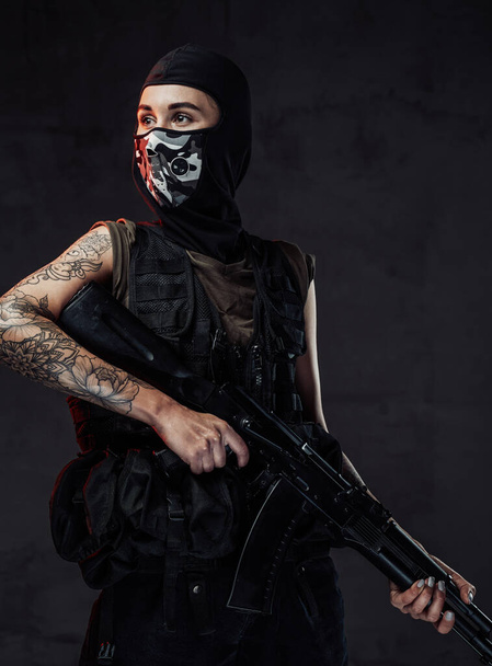 Menina sedutora vestida com máscara segurando rifle no fundo escuro - Foto, Imagem