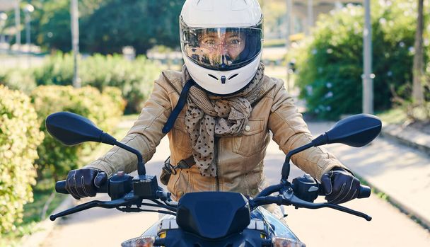 Ευτυχισμένη ποδηλάτης γυναίκα με τη μοτοσικλέτα της στους δρόμους μιας πόλης - Φωτογραφία, εικόνα