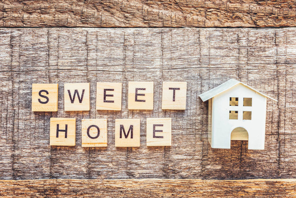 Miniature toy house with inscription SWEET HOME letters word on wooden background. Mortgage property insurance dream home concept. Flat lay top view copy space - Foto, Imagen