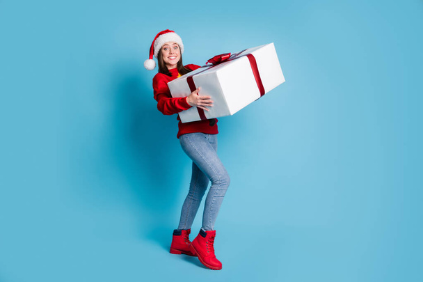 Photo portrait of cheerful woman lifting huge white wrapped giftbox isolated on pastel light blue colored background - Foto, Imagem