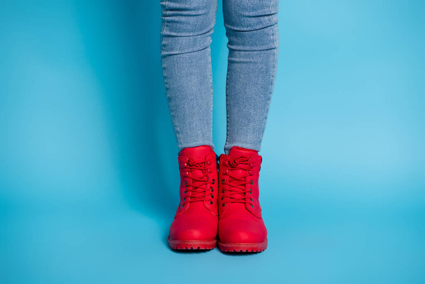 Cropped photo of slim lady legs standing alone wear stylish expensive red shoes boots sneakers denim jeans isolated blue color background - Zdjęcie, obraz