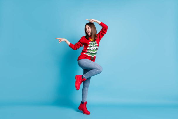 Full length body size photo of pretty brunette smiling standing tiptoe on one leg pointing with fingers on both hands at right side isolated on blue color background - Photo, image