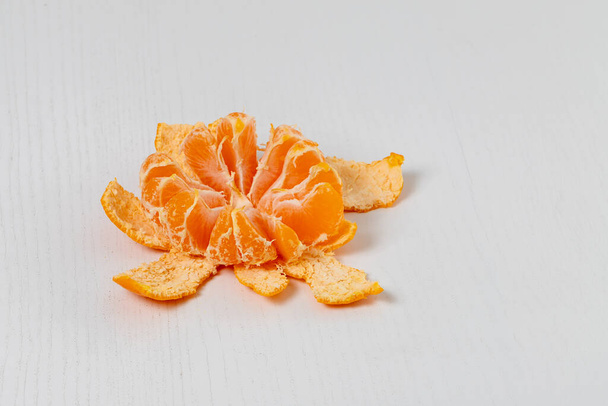 Mandarino in una buccia di spacco su un tavolo bianco. - Foto, immagini