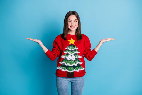 Photo of girl in christmas tree jumper pullover hold hand present x-mas discounts isolated over blue pastel color background - Foto, afbeelding
