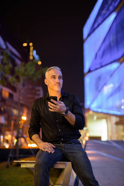 Homme attrayant la nuit dans les rues avec des lumières de la ville plan vertical - Photo, image