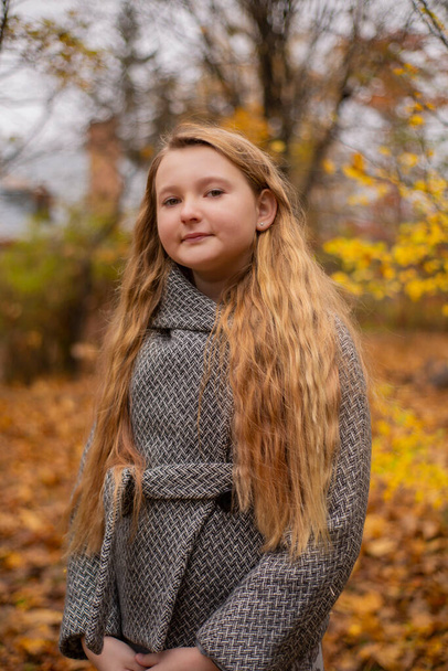 portrait of cute brunette teen girl in gray coat in the autumly forest . Cosiness, autumn. - Photo, Image