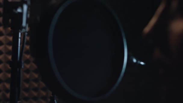 Vista posteriore del bel cantante rap maschile in cuffia con microfono professionale che canta la nuova canzone in studio moderno. Produzione musicale. Povera luce - Filmati, video