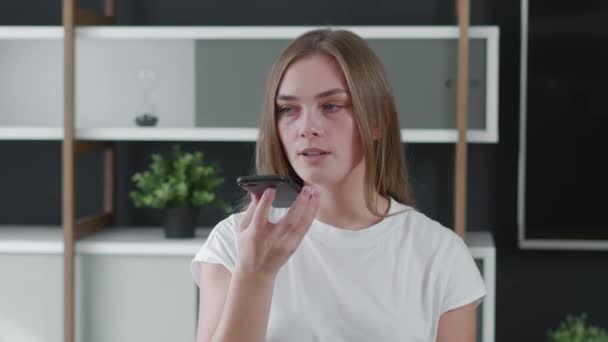 Young woman recording audio message in social network for friends. Attractive millennial girl sending voice message on her smartphone at home office. - Footage, Video