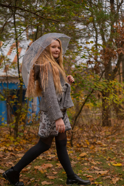 linda hermosa chica morena adolescente en un sombrero naranja, vestido y abrigo caminando con un paraguas transparente. Acogimiento, otoño. - Foto, imagen