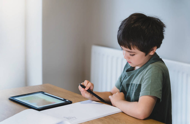 Új normális élet gyerek használ táblagépet a házi feladat, Gyermek fiú csinál házi feladatot segítségével digitális táblagép keresési információk az interneten, E-learning, Otthoni iskolai oktatási koncepció - Fotó, kép