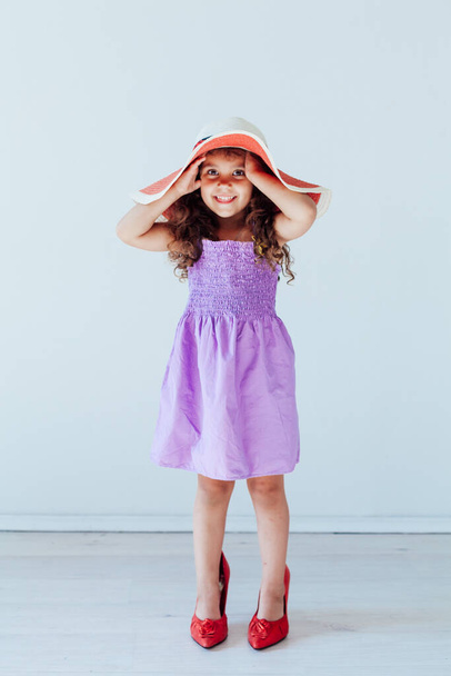 Little curly fashionable girl in a hat with fields - Фото, изображение