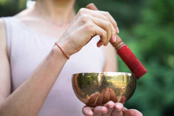 Медитація з вібраціями від чаші в положенні лотоса. Природа йоги теми руки і бронзовий посуд. музика душі на інструменті
 - Фото, зображення