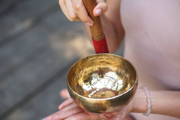 Meditazione con vibrazioni dalla ciotola nella posizione del loto. Natura yoga mani a tema e utensili in bronzo. musica soul su uno strumento - Foto, immagini