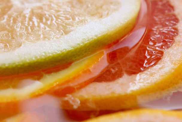 Grapefruit, orange, lime, tangerine, lemon slices in water. Background is made of citrus fruits. Pieces of citrus. Background is of multi-colored citrus fruits. Texture. Wallpapers. Vitamin Complex. - Fotoğraf, Görsel