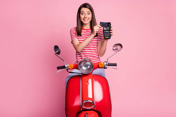 Portrait of her she nice attractive lovely cheerful cheery glad girlish amazed girl riding sitting on moped using pos terminal paying wireless transfer isolated over pink pastel color background - Zdjęcie, obraz