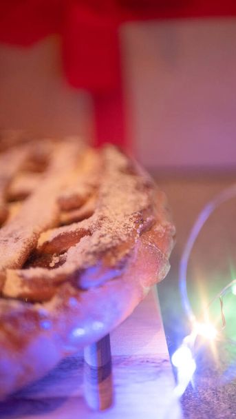tarta de manzana con luces de Navidad. y un regalo en el fondo - Foto, Imagen