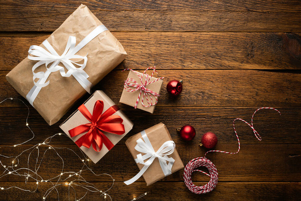 Vánoční dárky pokryté řemeslným papírem na dřevěném pozadí, horní pohled. Koncept zimních prázdnin - Fotografie, Obrázek