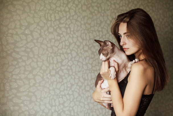 Boldog ázsiai nő fogja a macskáját. Bolyhos macska, a macska a kezén. Gyönyörű fiatal nő aranyos macska pihen otthon - Fotó, kép