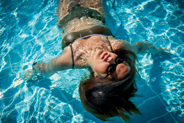 Portrait de mode de fille mignonne gracieuse dans des lunettes de soleil élégantes posant dans la piscine pendant les vacances sur la station de luxe. Joyeux plus la taille de l'adolescente profiter. heureux, émotion positive, style d'été. - Photo, image