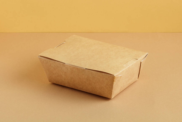 Caja de comida de papel marrón. Fondo de color tierra. Concepto de paquete reutilizable - Foto, Imagen