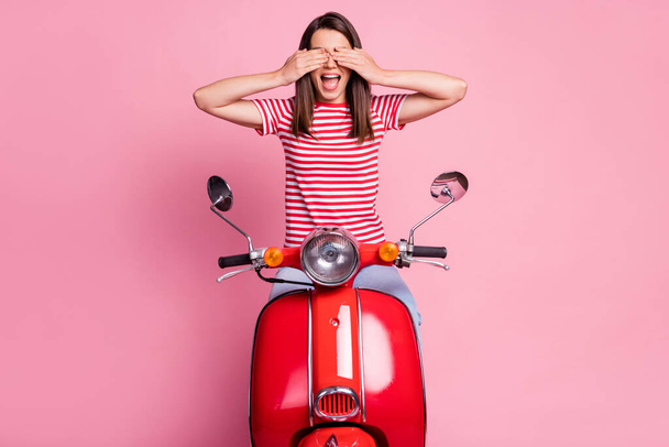 Photo portrait of female driver sitting on red motorcycle closing eyes with hands opened mouth isolated on pastel pink color background - Foto, imagen